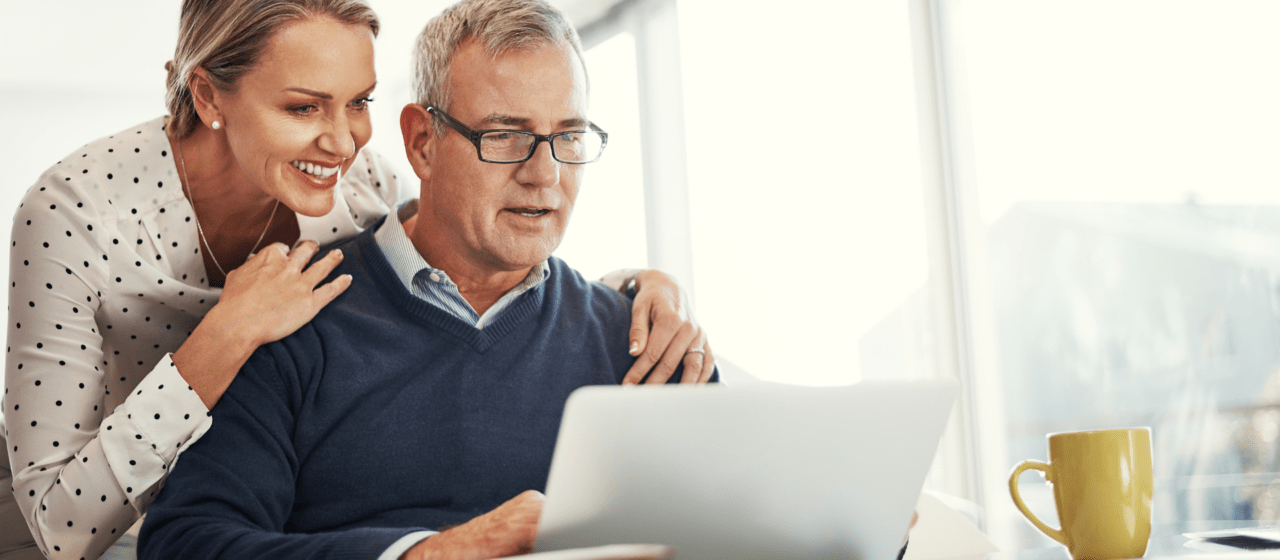 Two retirees sitting at a computer reviewing their retirement plan and finances