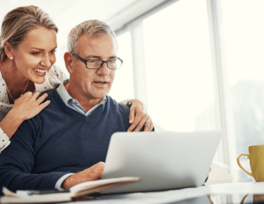 Two retirees sitting at a computer reviewing their retirement plan and finances