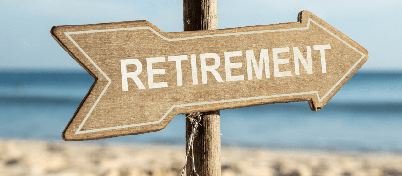 Wooden arrow sign reading "Retirement" pointing toward a beach, symbolizing the option to retire immediately