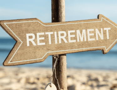 Wooden arrow sign reading "Retirement" pointing toward a beach, symbolizing the option to retire immediately